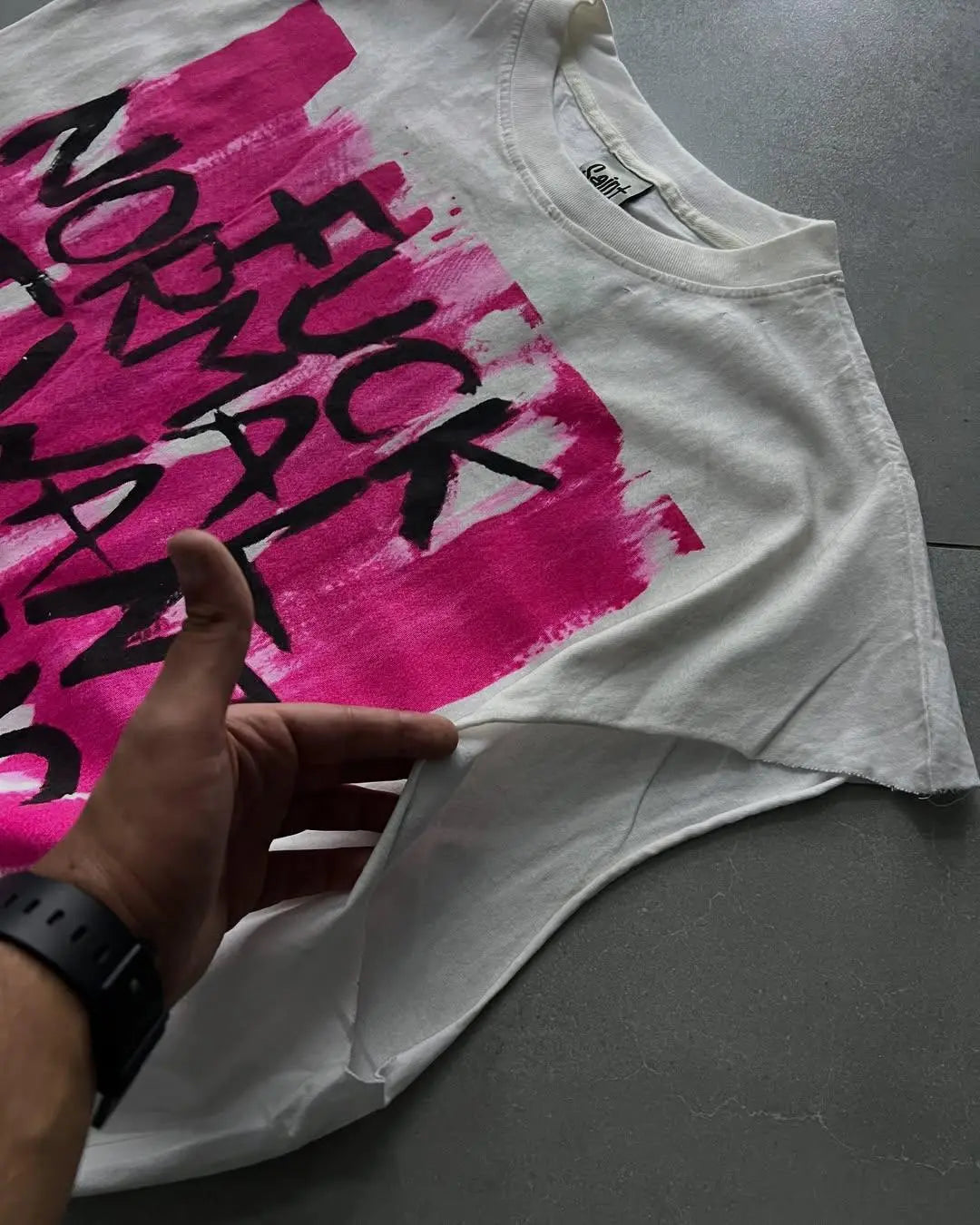 White tank top with pink and black text on a gray surface