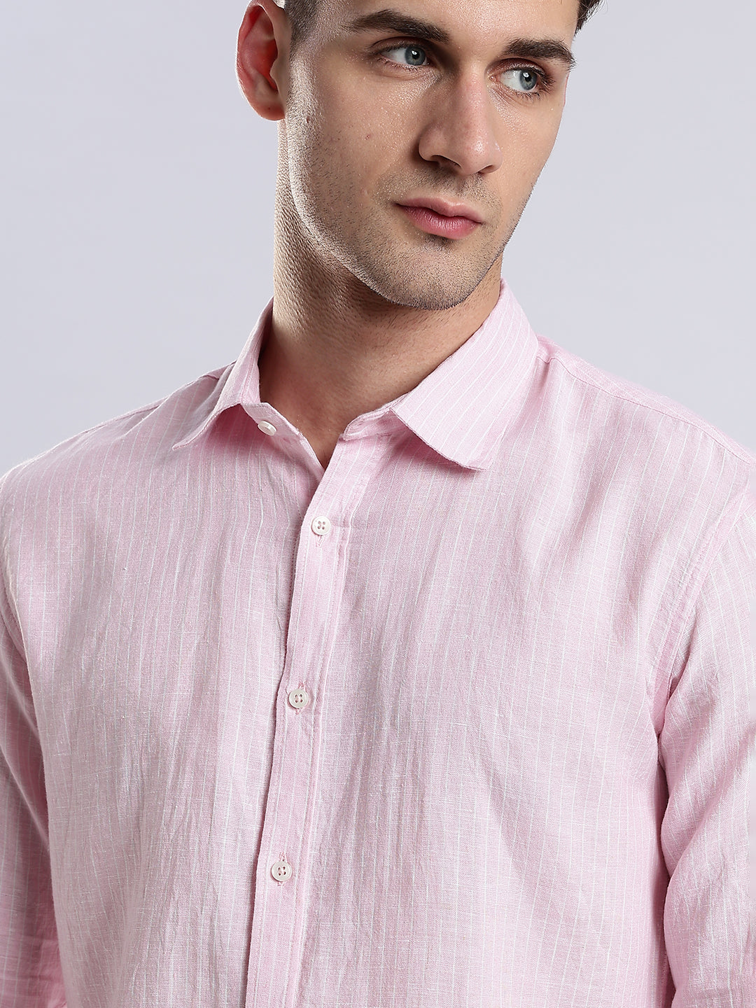 Detail of a structured spread collar on a pale pink textured linen button-down shirt.