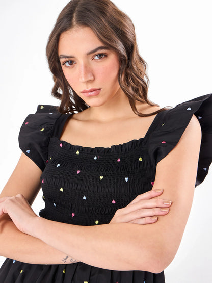 Female model wearing a sleeveless embroidered black romper from Stylera