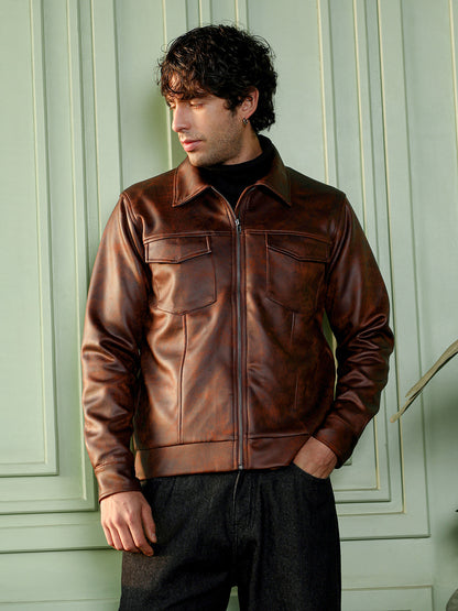 Man wearing a campus sutra's brown leather jacket against a light green wall.