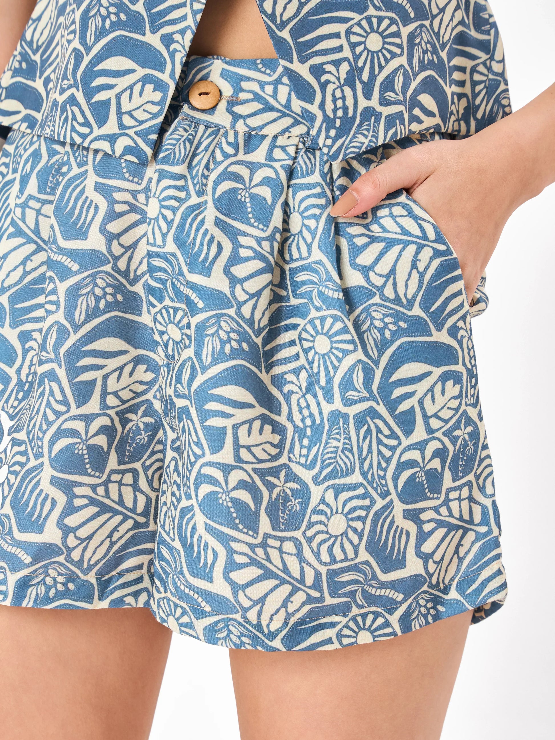 Female model wearing a blue patterned co-ord set includes crop top & button closure shorts from Stylera