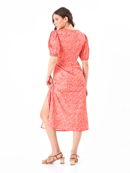 Female model wearing a coral pink floral dress from Stylera, showcasing backside