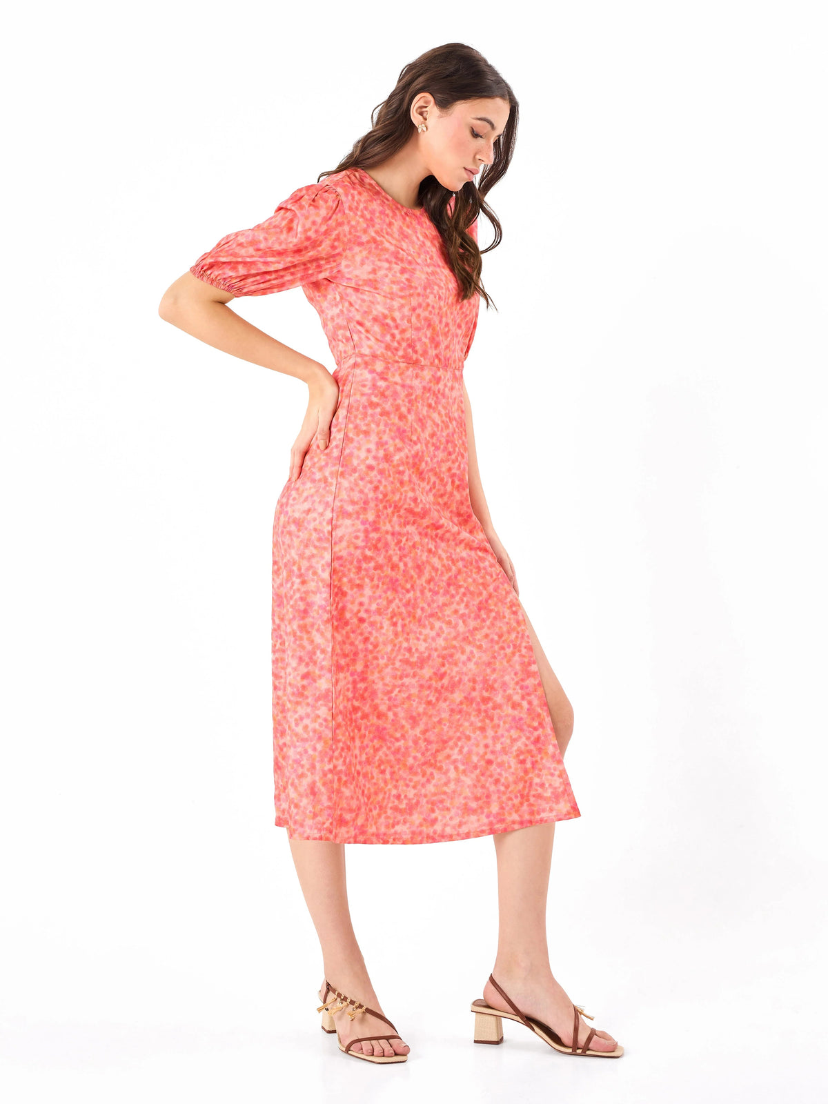 Female model wearing a coral pink floral dress from Stylera, showcasing side angle