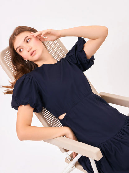 Female model wearing a navy blue dress from Stylera. styling over chair