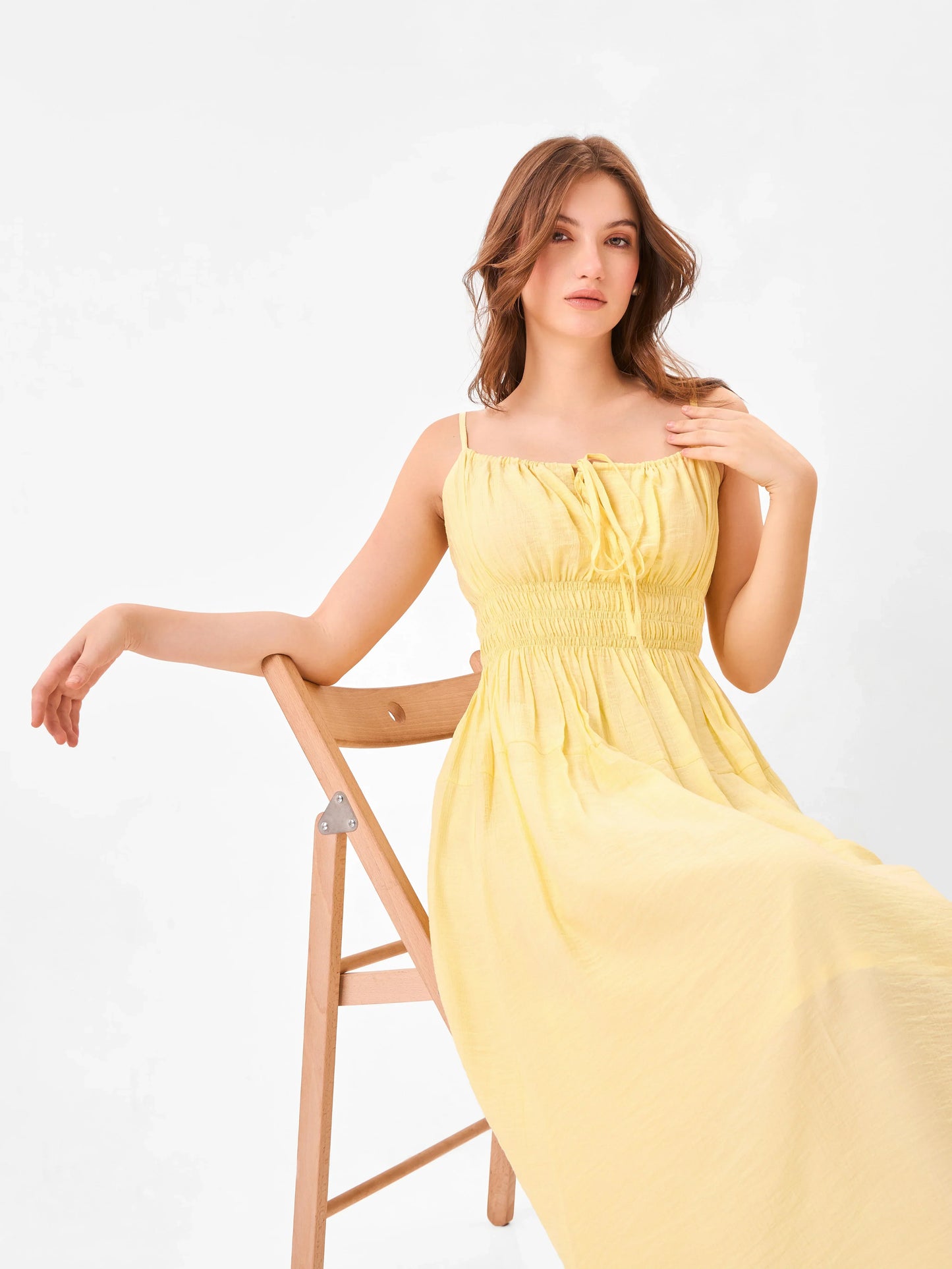 Female model wearing a yellow midi dress with the knot detail from Stylera