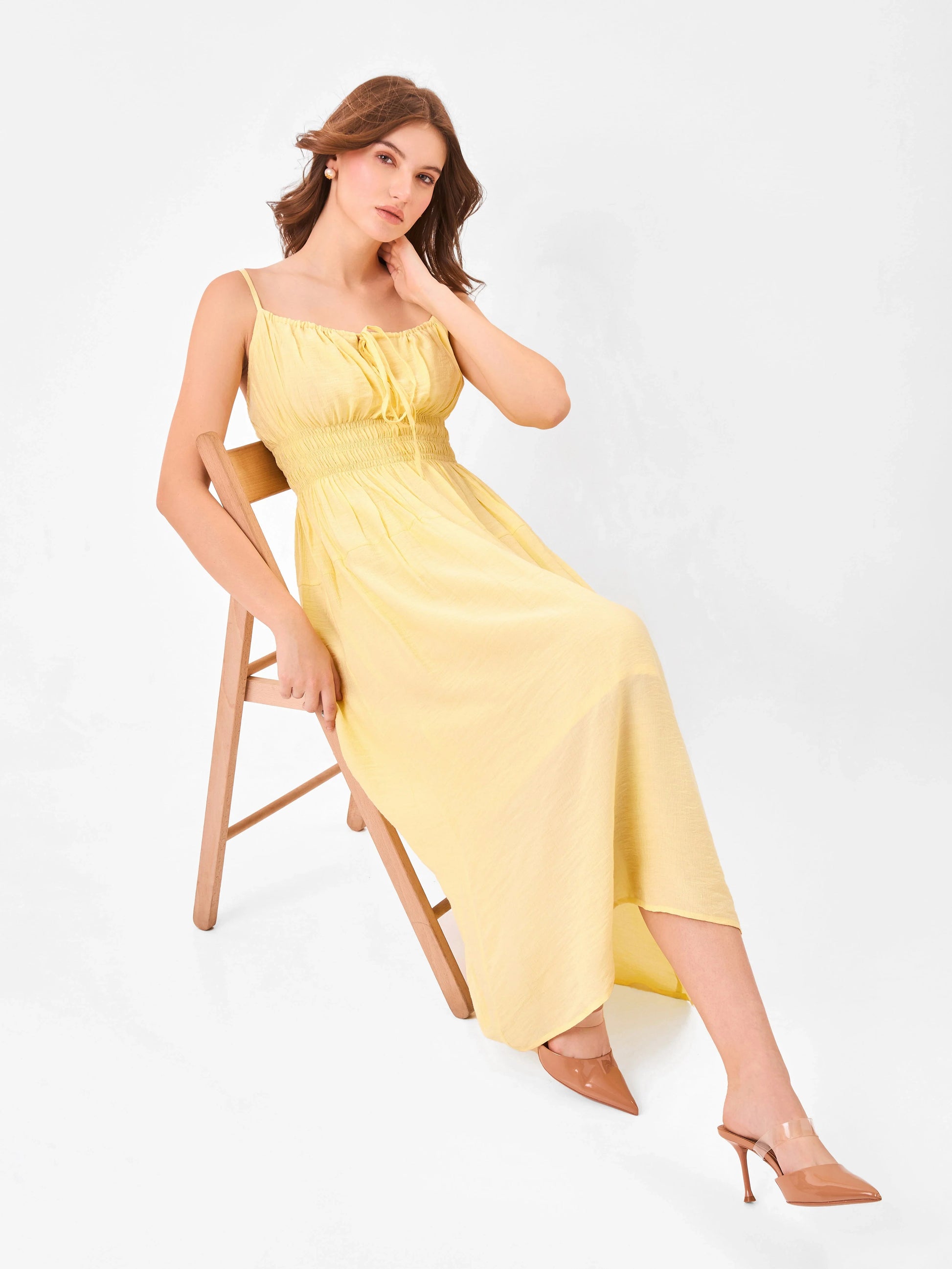 Female model wearing a yellow midi dress from Stylera, styling over chair