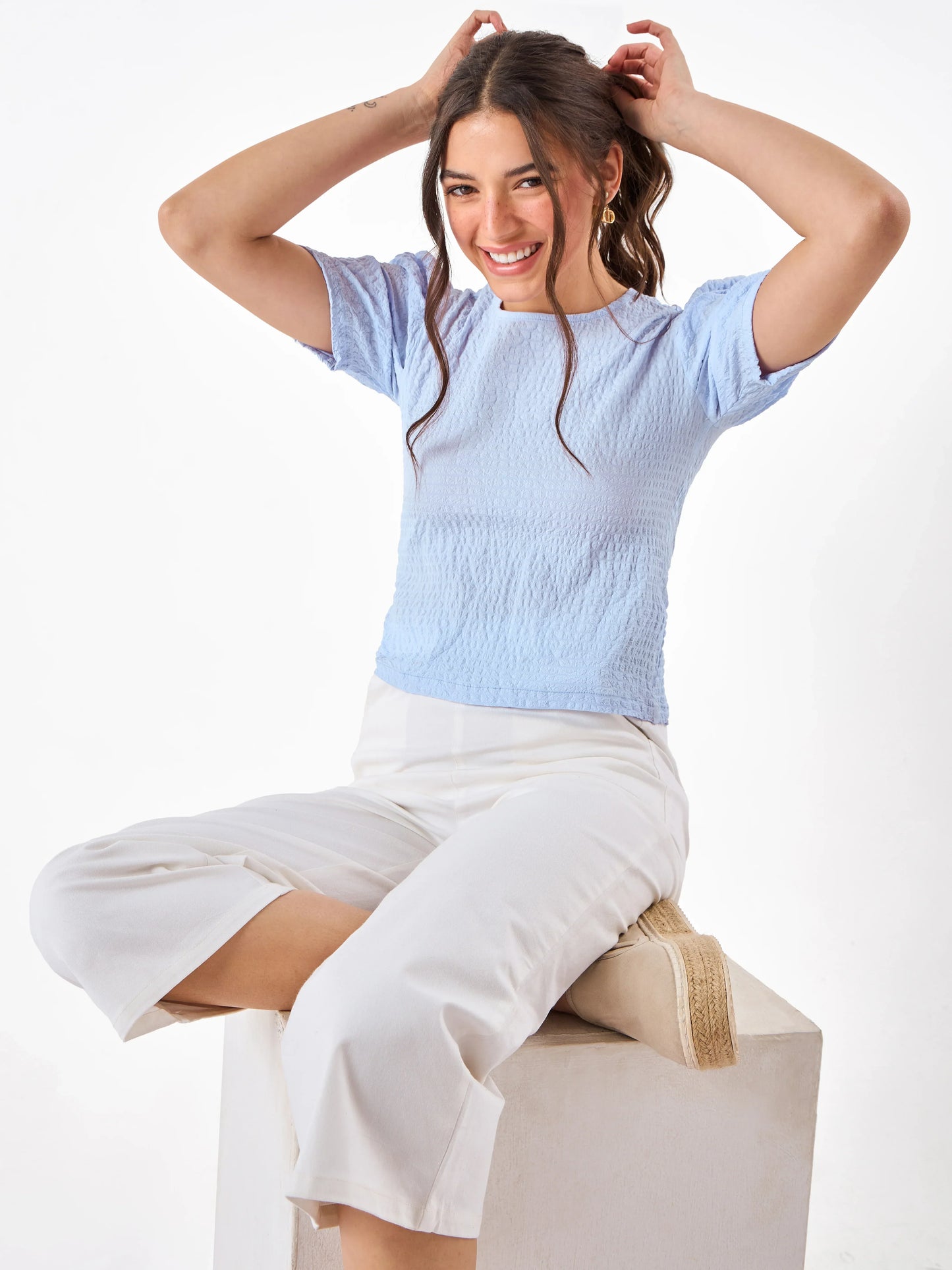 Female model wearing a light blue top pairing with white pant from Stylera
