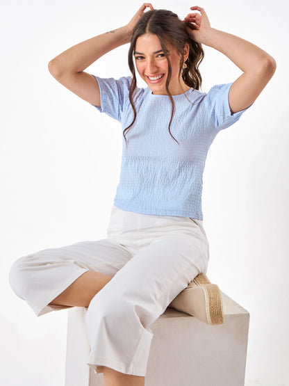 Female model wearing a light blue top pairing with white pant from Stylera