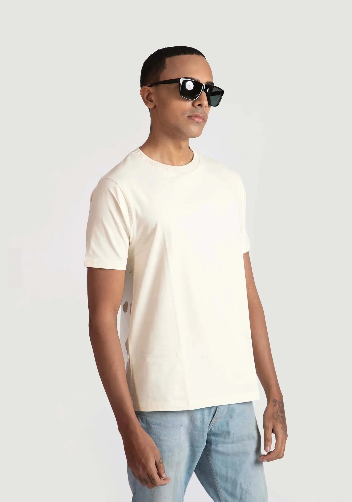 Stylera men's trendy cream t-shirt worn by model with sunglasses and light blue jeans