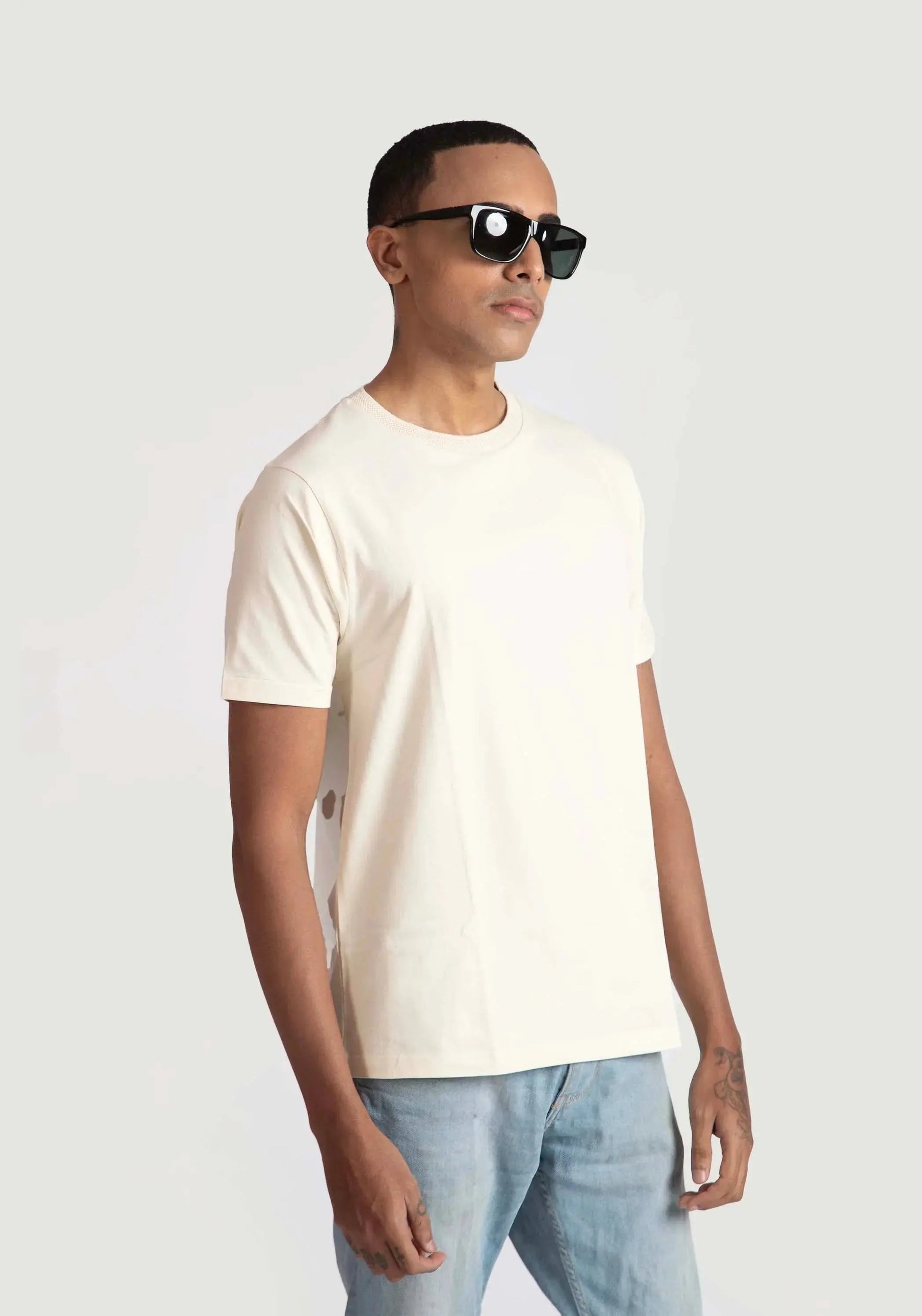 Stylera men's trendy cream t-shirt worn by model with sunglasses and light blue jeans