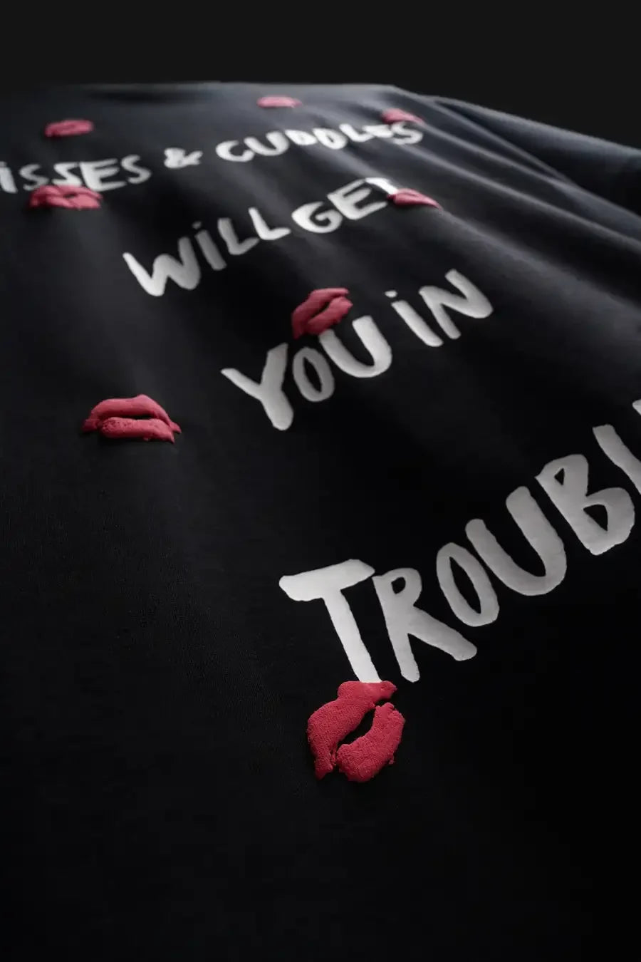 Black shirt with white text and red lip prints on a dark background