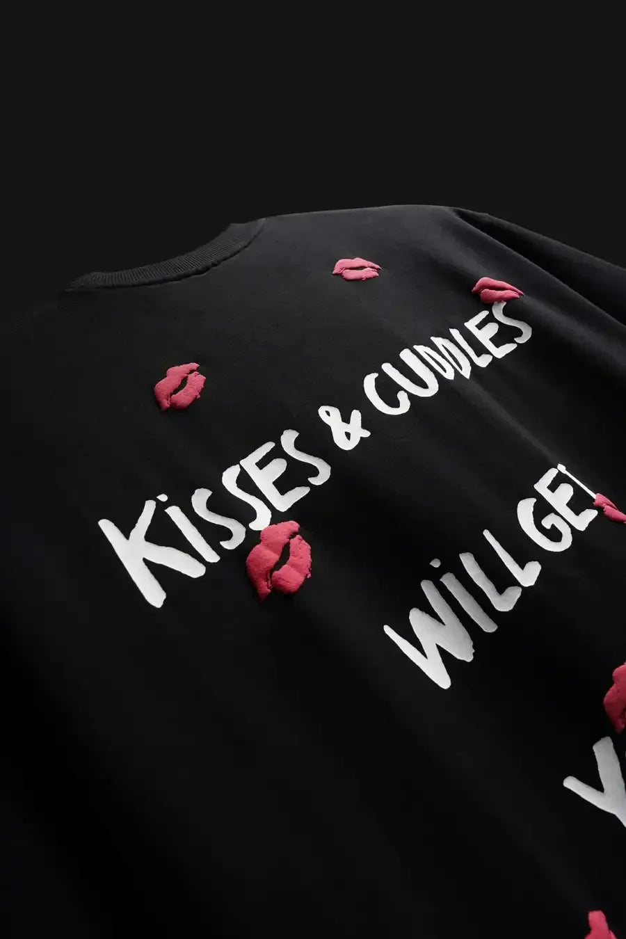 Black shirt with white text 'Kisses & Cuddles Will Get You' and red lip prints on a dark background