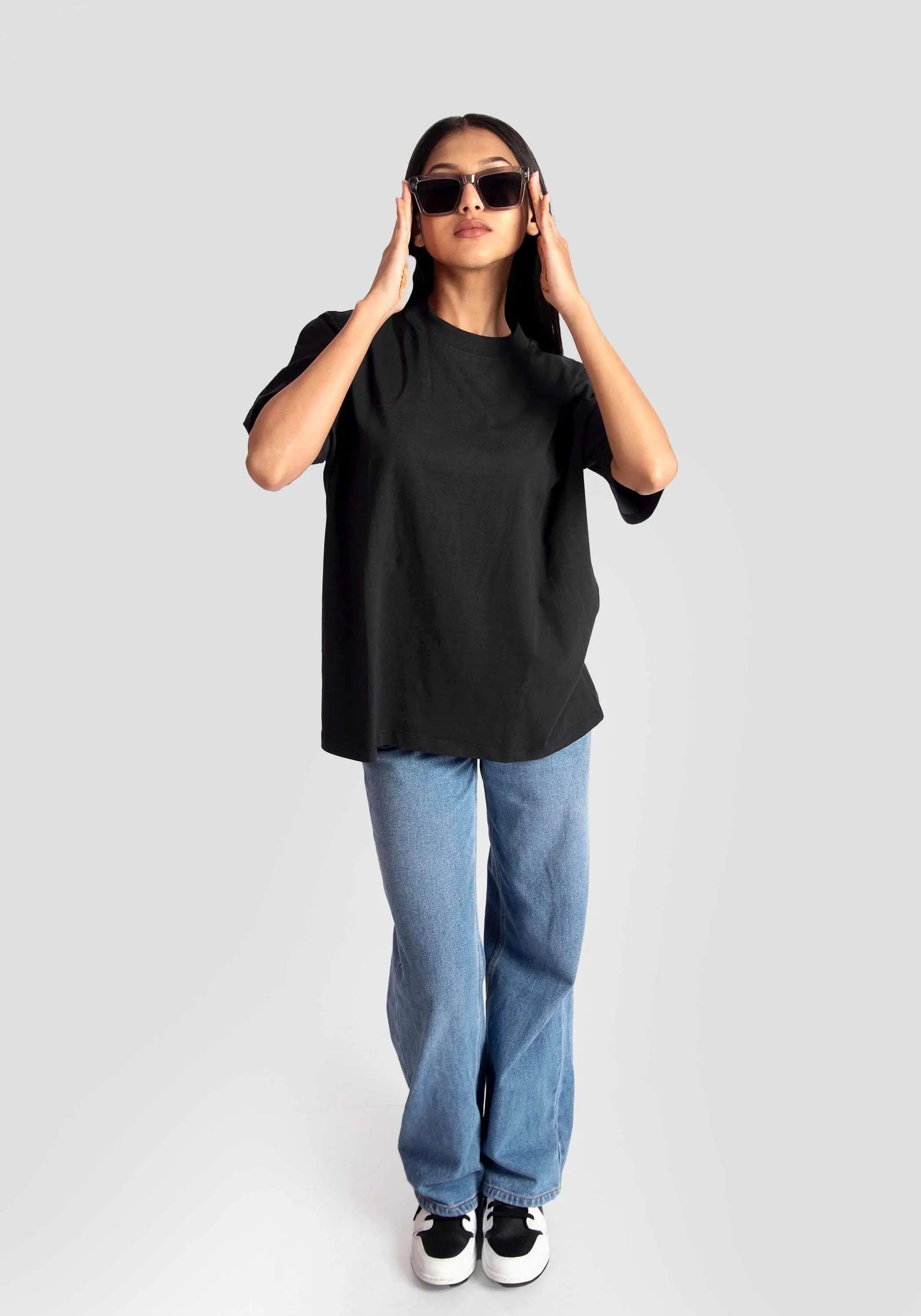 Woman wearing black streetwear oversized tee womens with blue jeans and sunglasses by Stylera