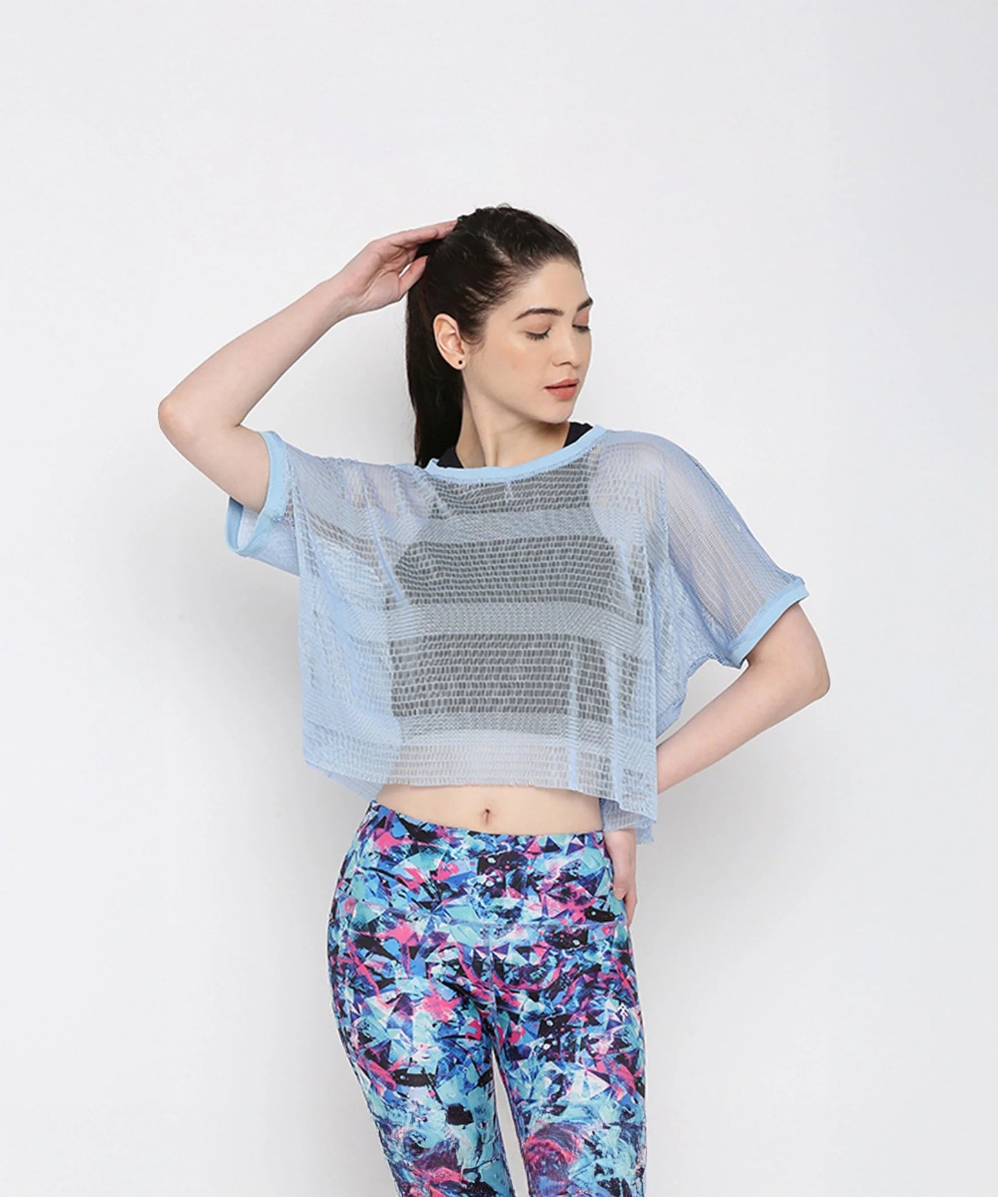 Blue netted top for women layered over a black sports bra, styled with colorful workout leggings