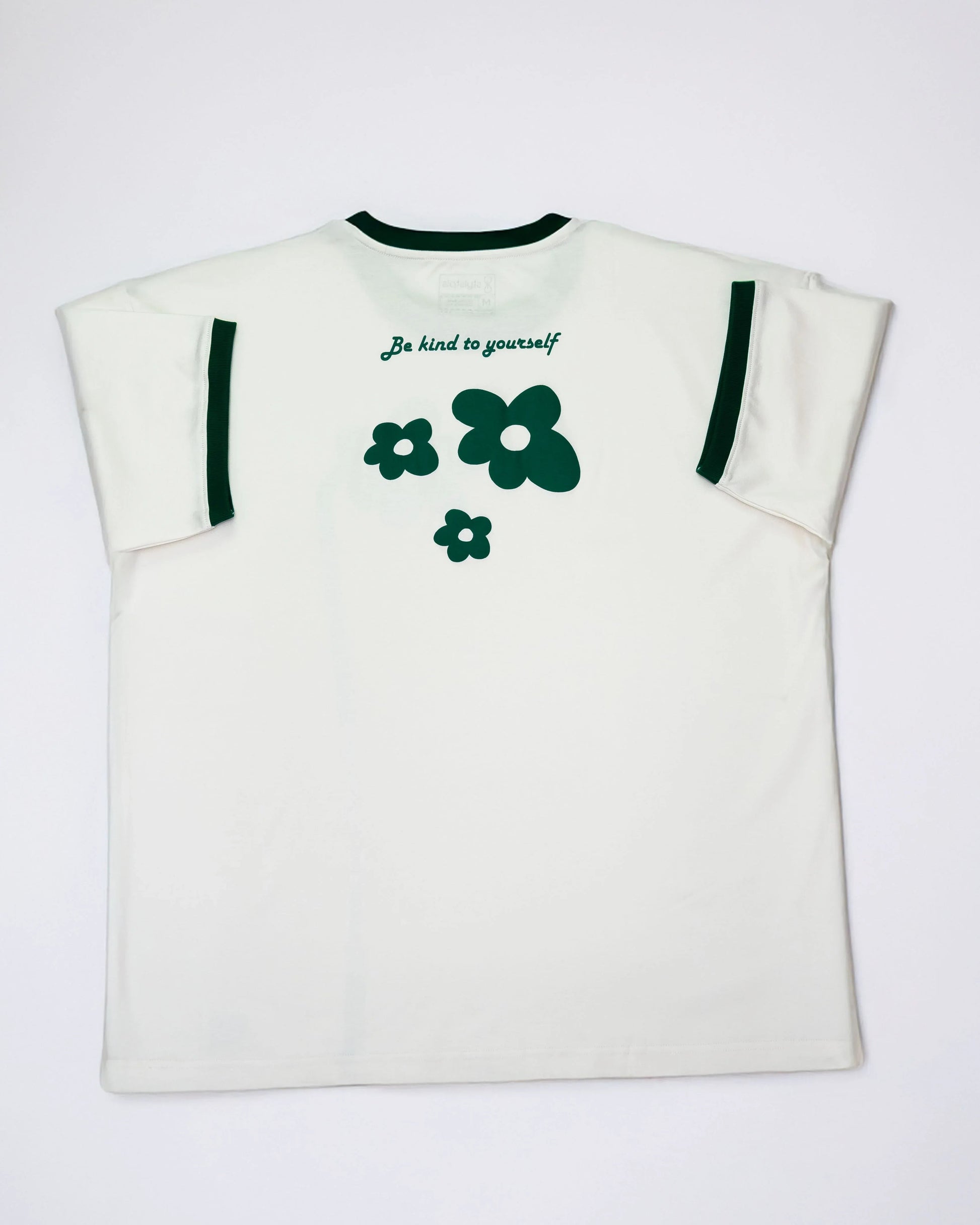 Cream oversized flower t-shirt featuring green flower graphics and a kindness message on the back