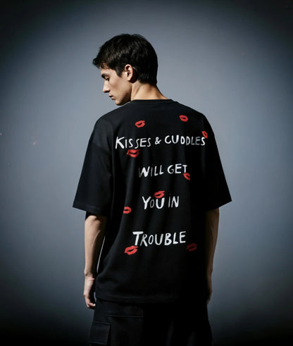 Person wearing a black t-shirt with text and red lip prints on a gray background