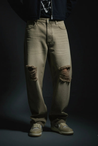 Person wearing distressed beige jeans on a dark background