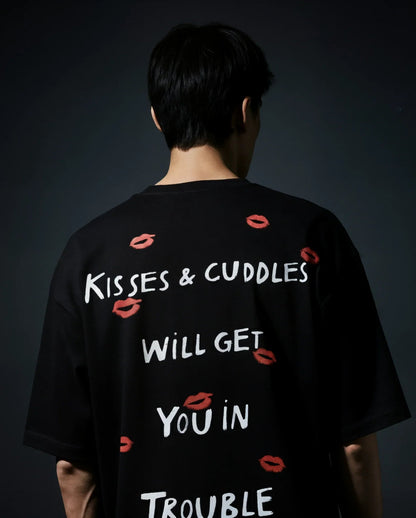 Person wearing a black t-shirt with text and red lip prints on a dark background