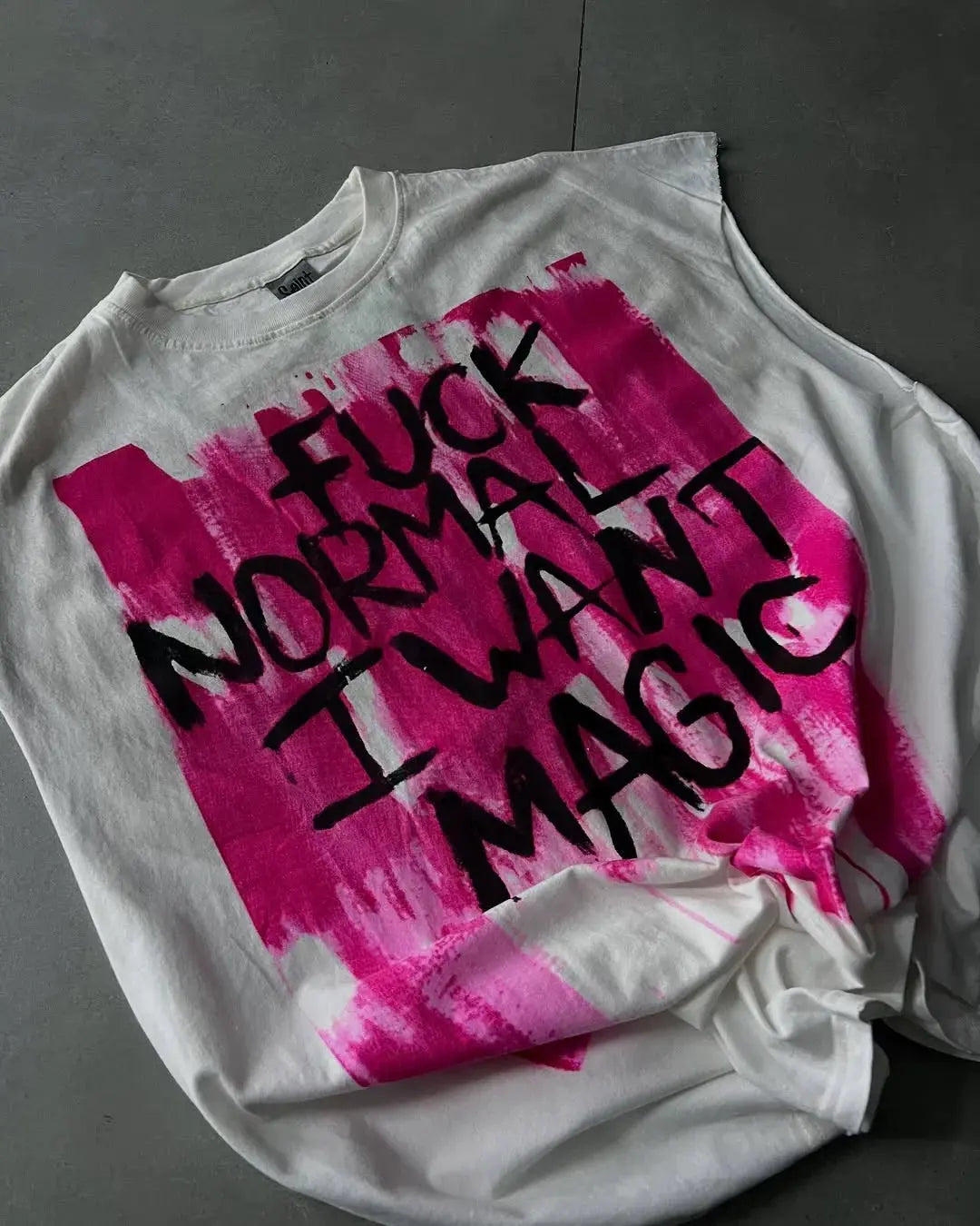 White t-shirt with pink and black text on a gray surface