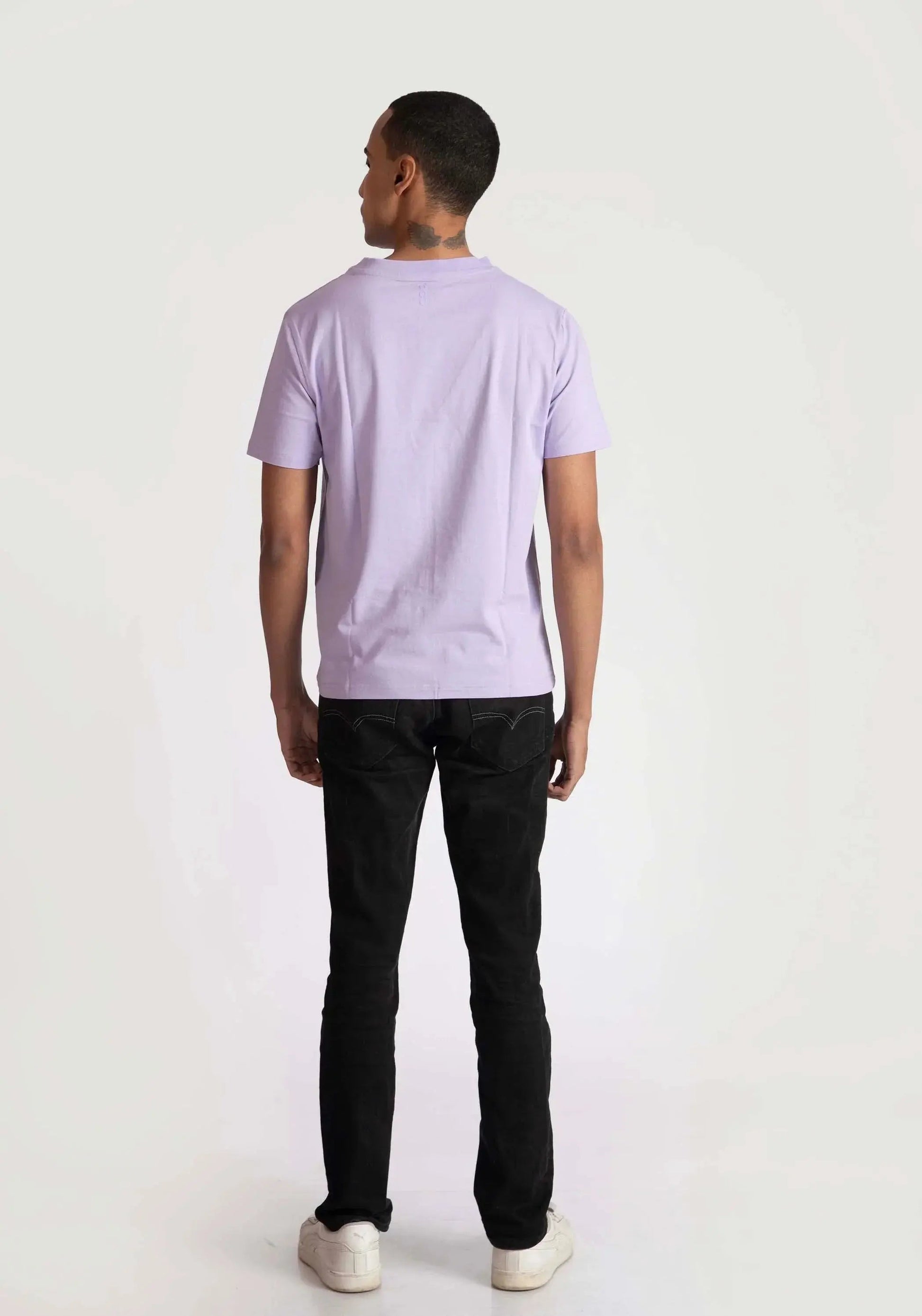 Back view of a man wearing Stylera men's regular fit trendy t-shirt in light purple with black pants