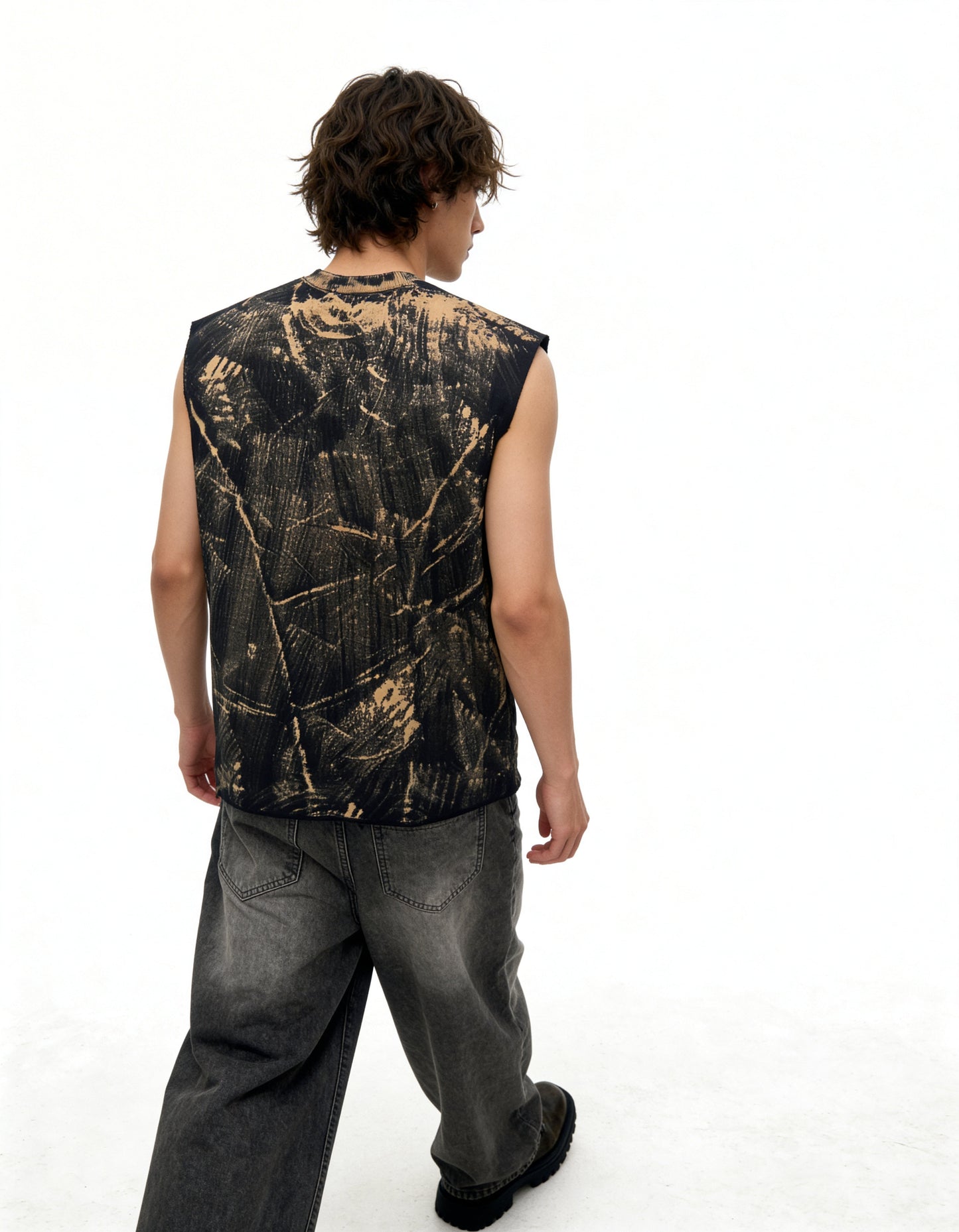 Person wearing a sleeveless black and gold patterned shirt on a white background
