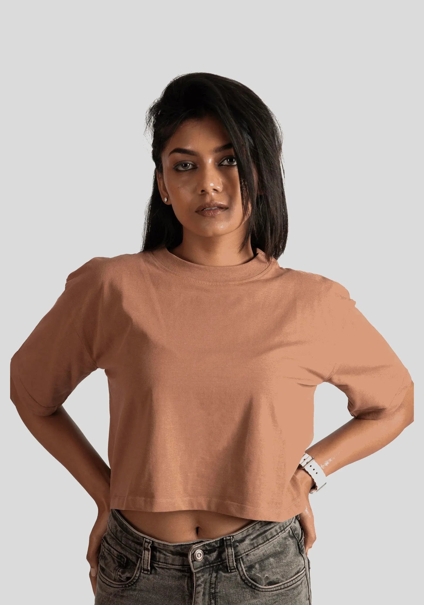Woman wearing Stylera mocha oversized crop top paired with denim jeans against a plain background