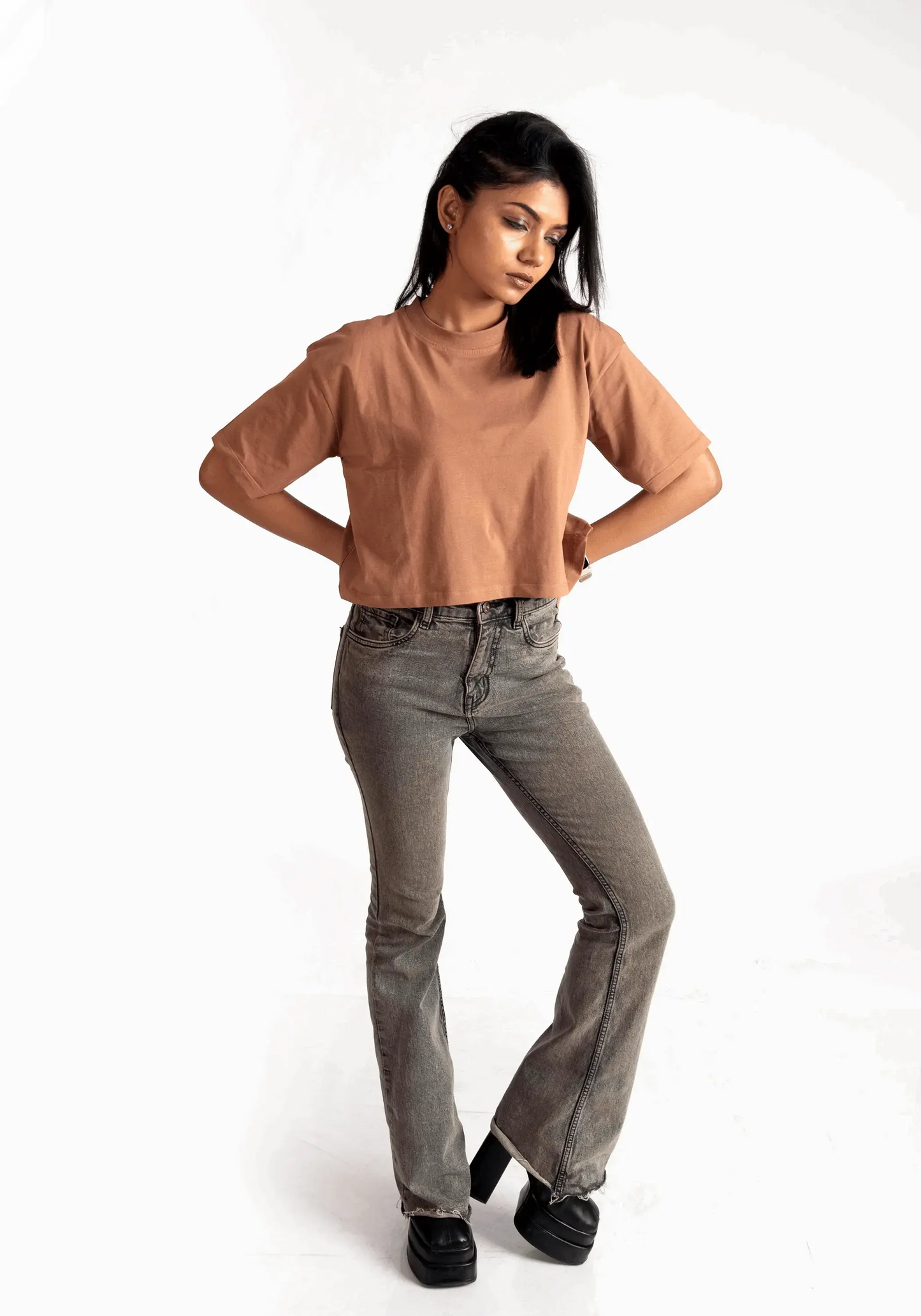 Woman wearing mocha oversized crop top from Stylera paired with gray jeans and black shoes