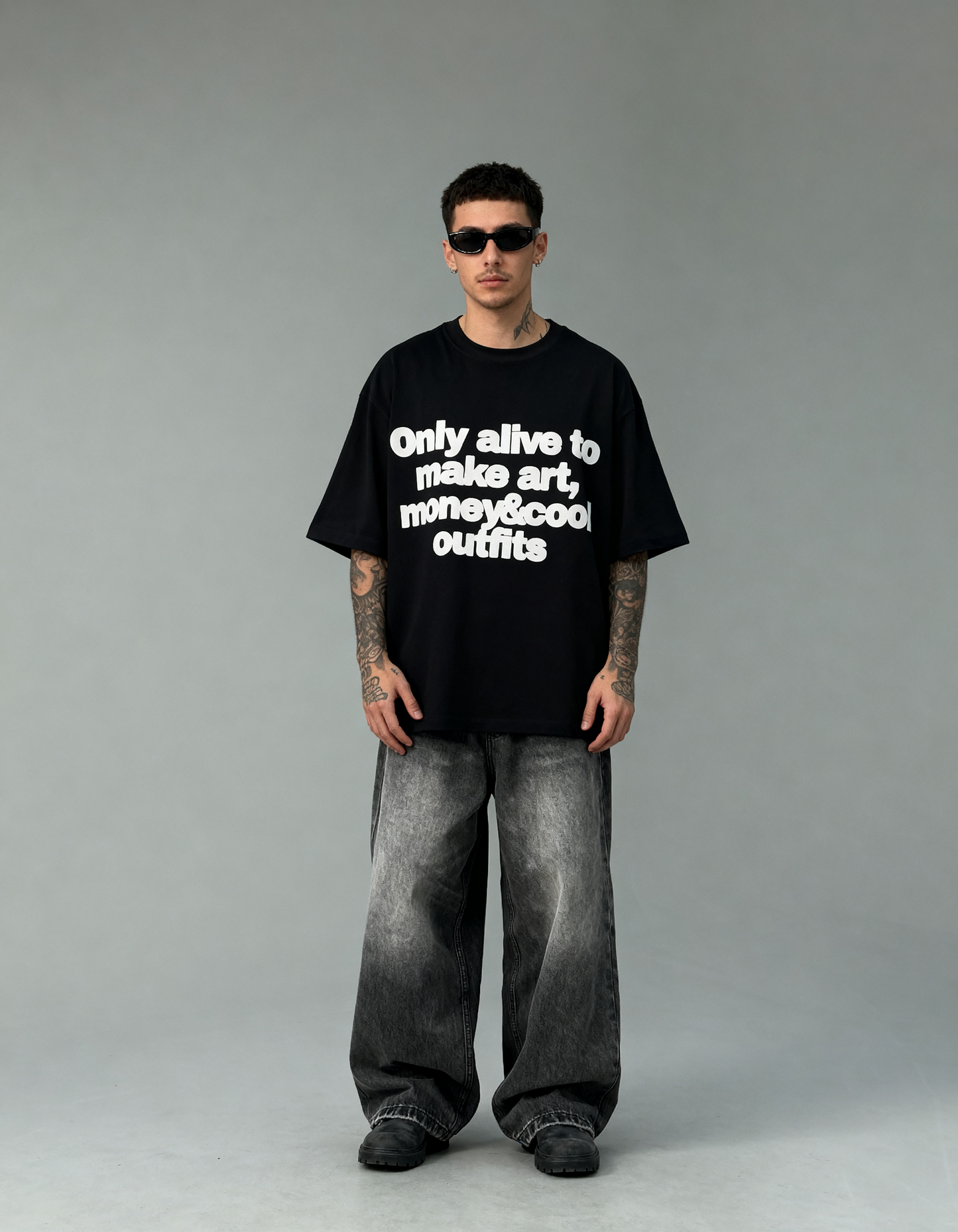 Person wearing a black t-shirt with text and gray pants on a gray background