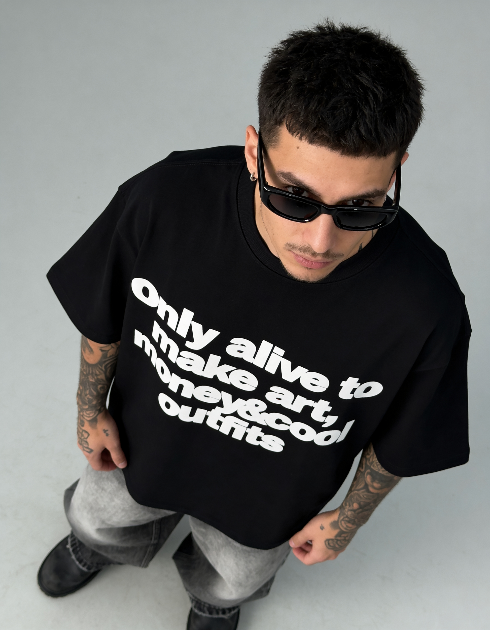 Person wearing a black t-shirt with white text, standing against a plain background