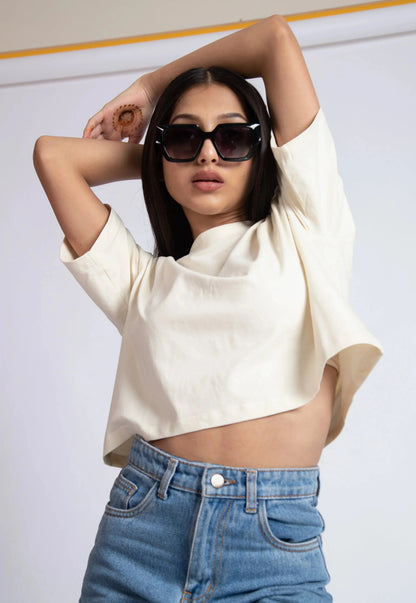Woman wearing oversized crop top for women in white paired with high waist blue jeans and sunglasses