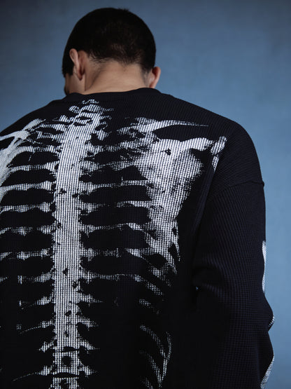 Person wearing a sweater with a skeleton design on the back against a blue background
