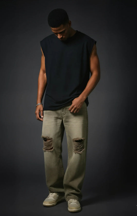 Man wearing a black sleeveless shirt and light-colored jeans against a dark background