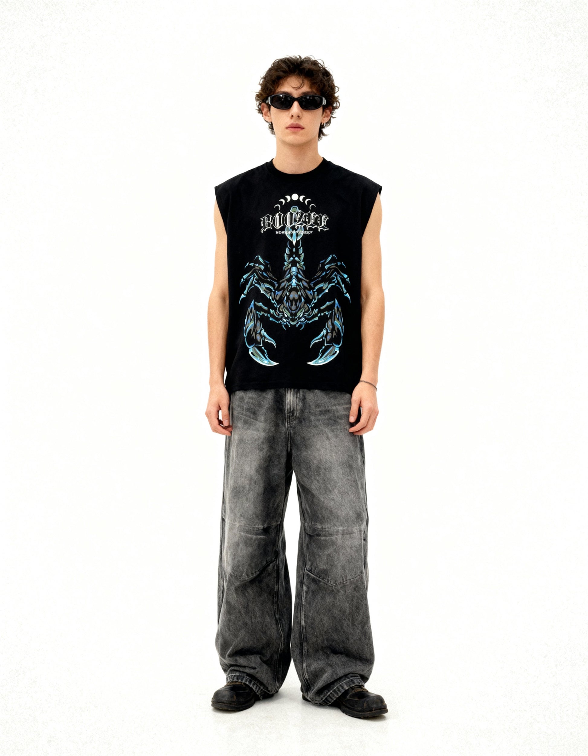 Person wearing a black sleeveless shirt with a graphic design and gray pants on a white background