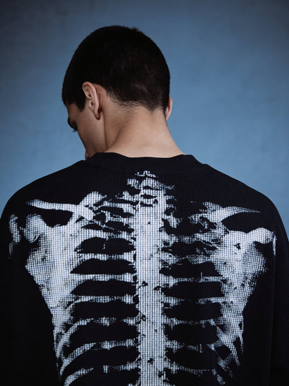 Person wearing a black sweater with a digital skeleton design on the back against a blue background