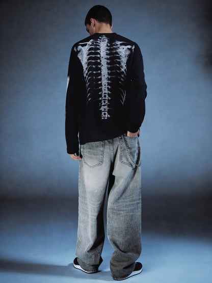 Person wearing a black sweater with a white skeleton design on the back against a gray background
