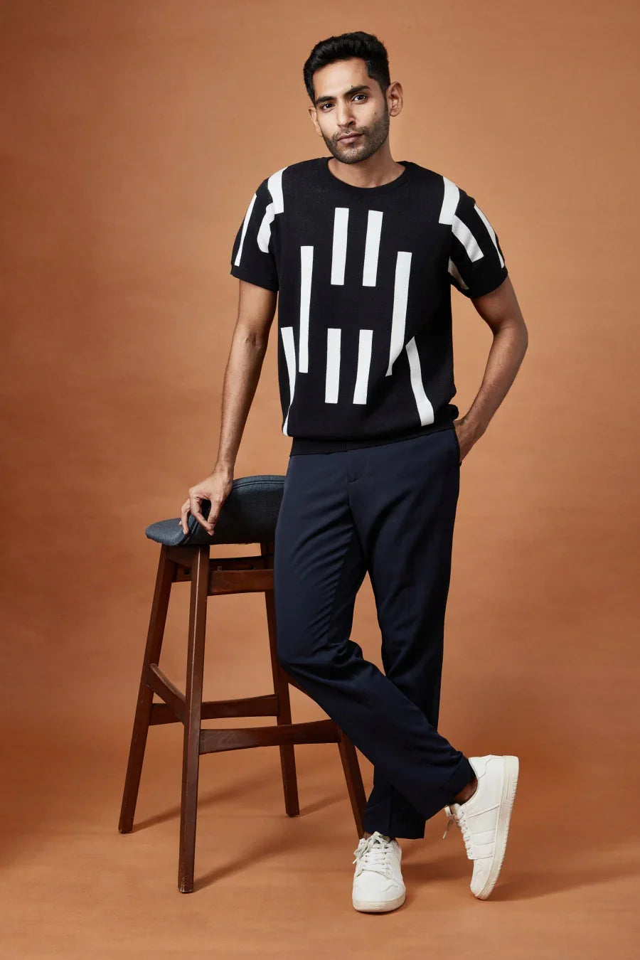 Trendy casual black tee with bold white geometric patterns, styled with navy pants and white sneakers