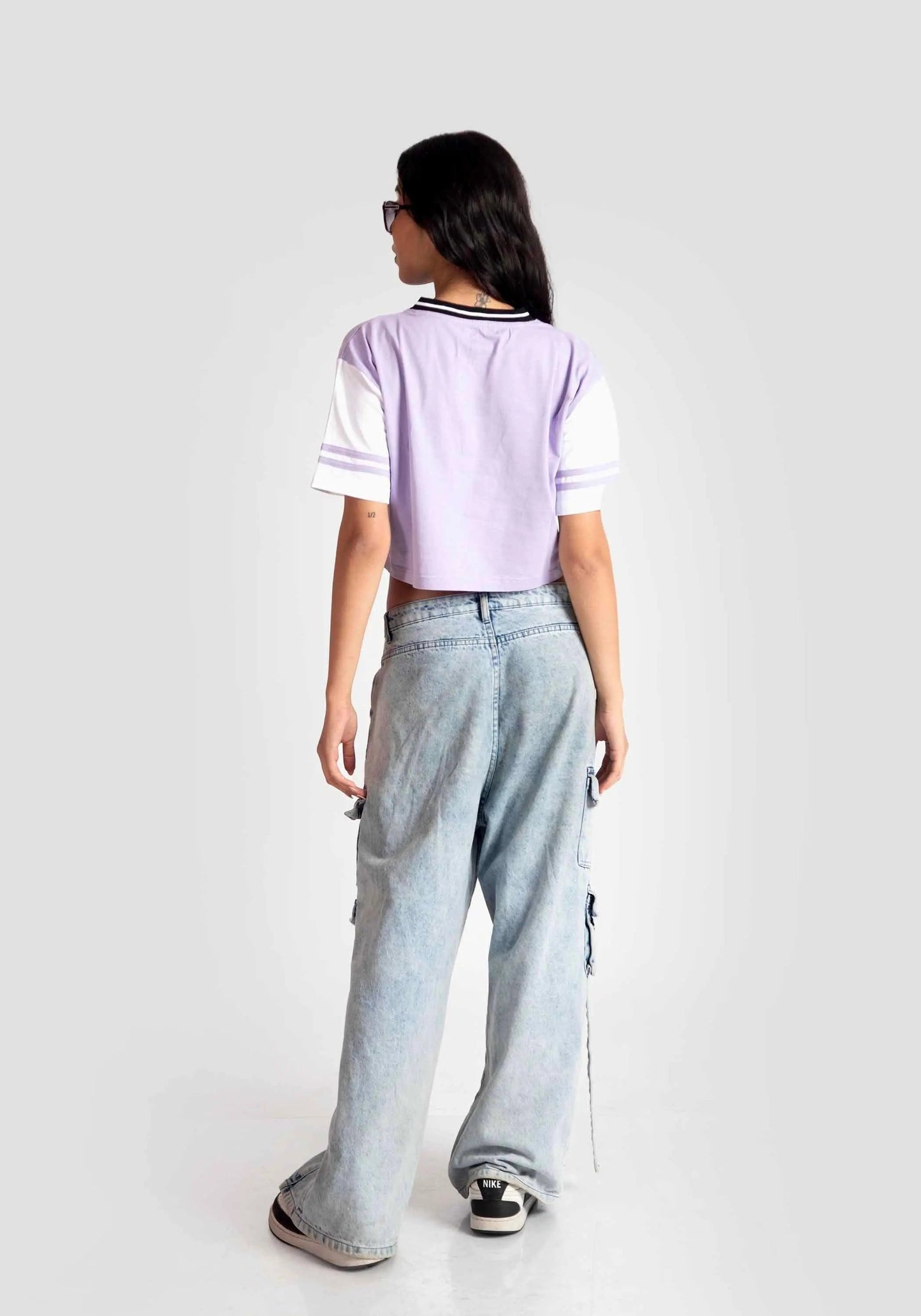 Back view of a woman wearing trendy casual tops for women in lavender and white paired with wide-leg jeans