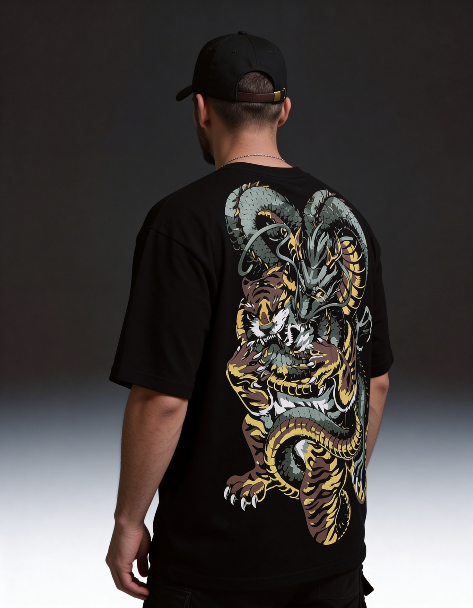 Person wearing a black t-shirt with a colorful dragon design on the back against a dark background