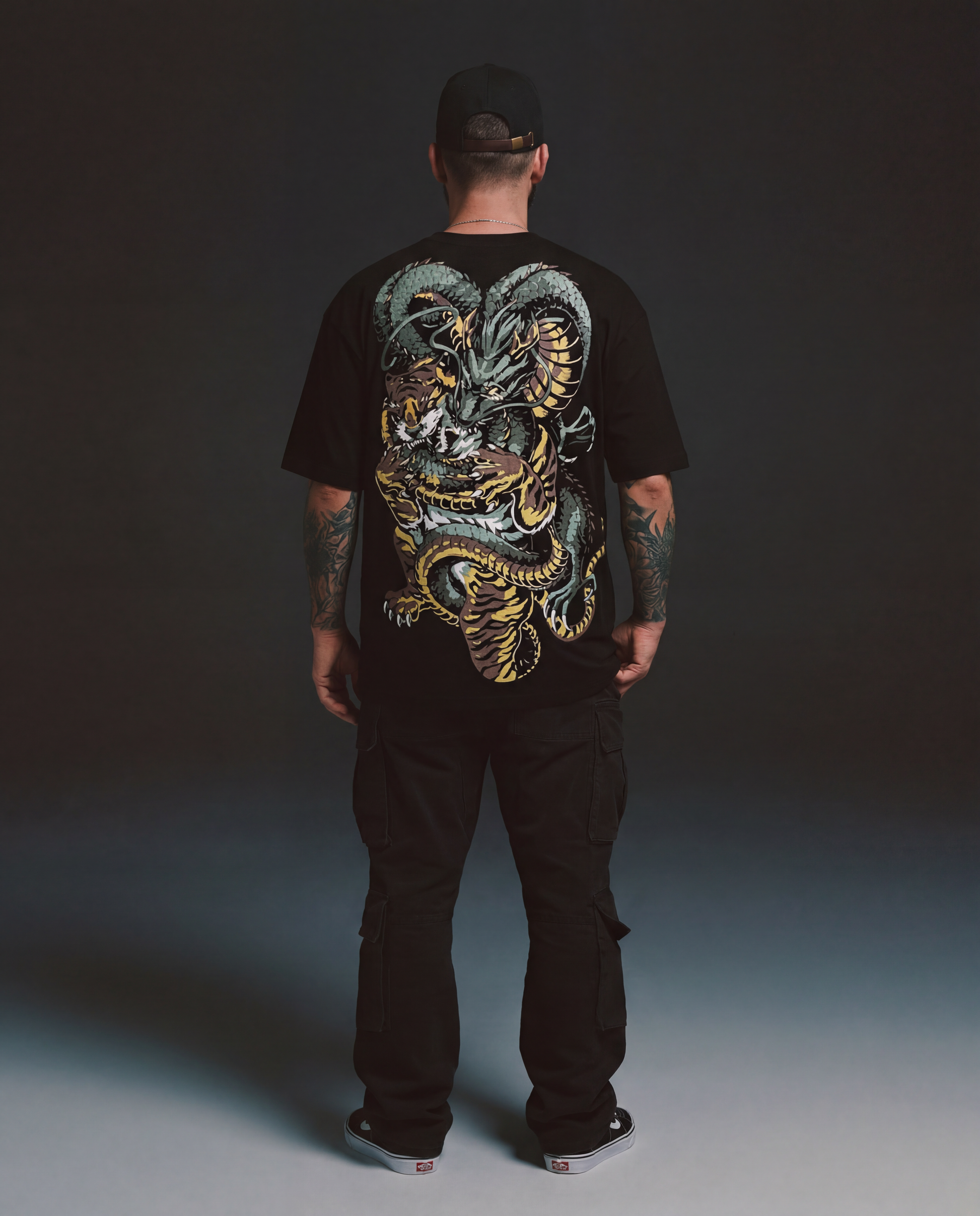 Person wearing a black t-shirt with a colorful dragon design on the back against a dark background
