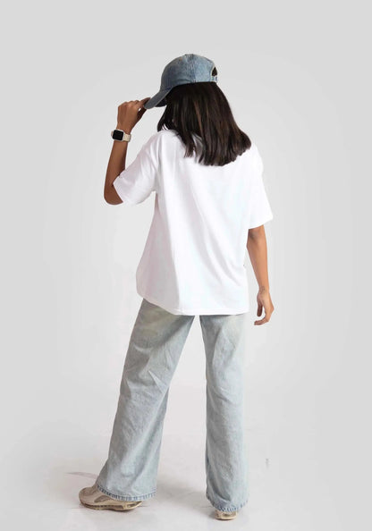 Woman wearing a white good vibes only graphic tee for women with light wash jeans and a blue cap
