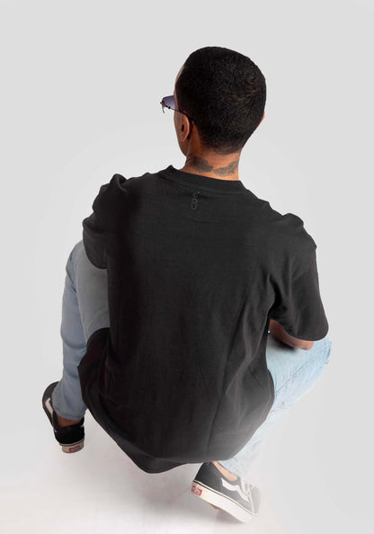 Man wearing black oversized graphic t-shirt from Stylera Lifestyle paired with light blue jeans and black sneakers